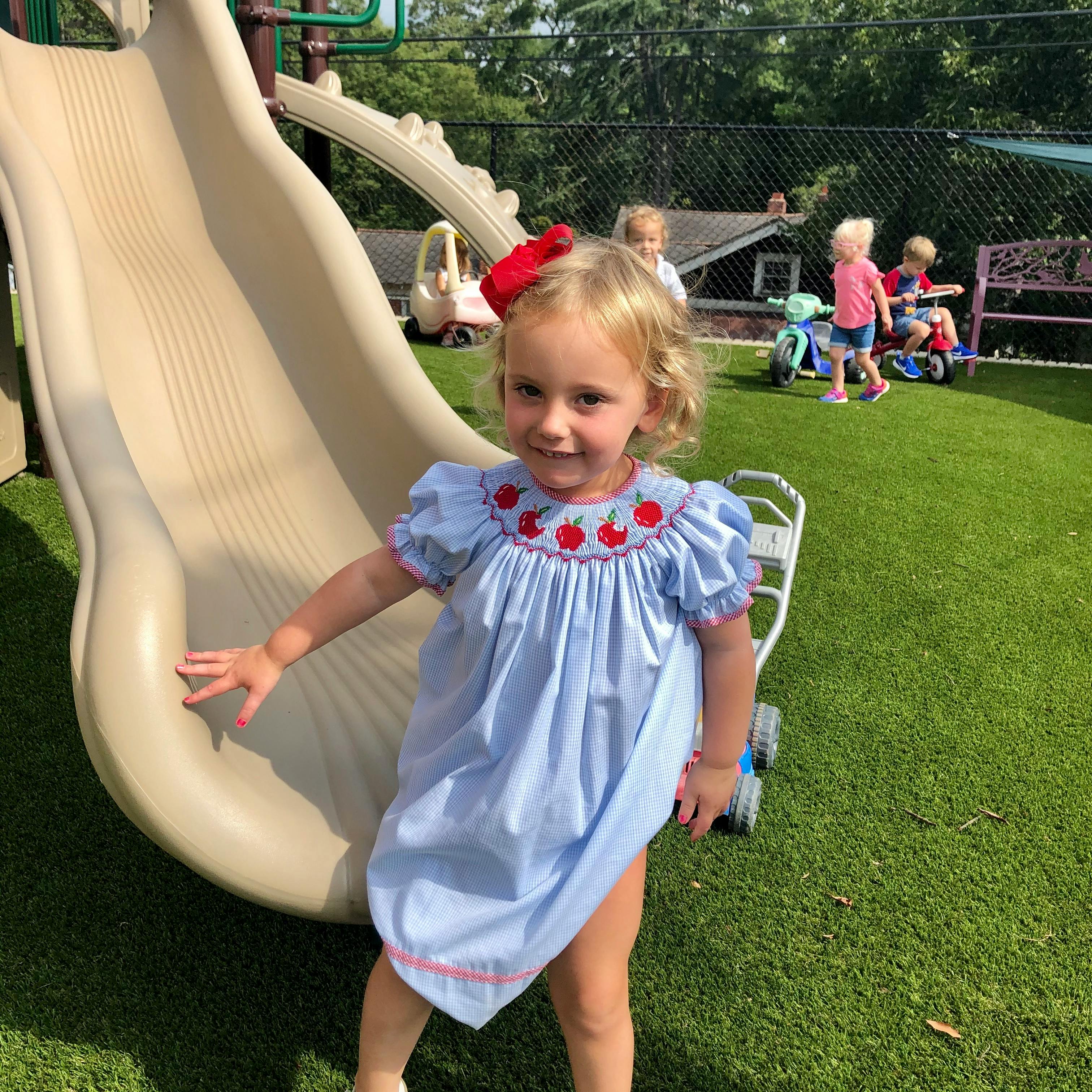 Child standing next to a slide on a playground