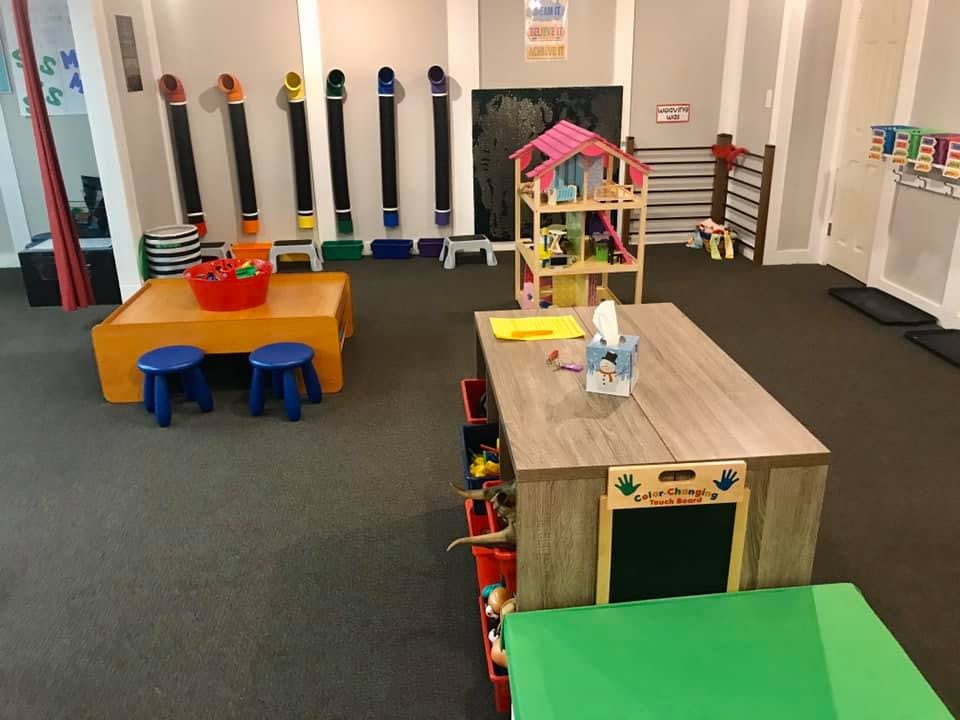 Playroom with tables, stools, and a dollhouse