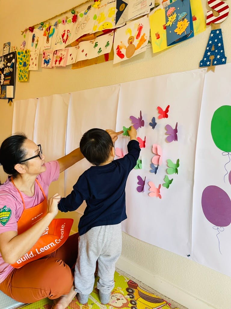 Person and child placing butterfly cutouts on a white sheet
