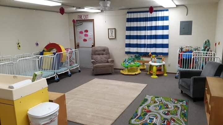 Room with multiple cribs, a changing table, and play mats