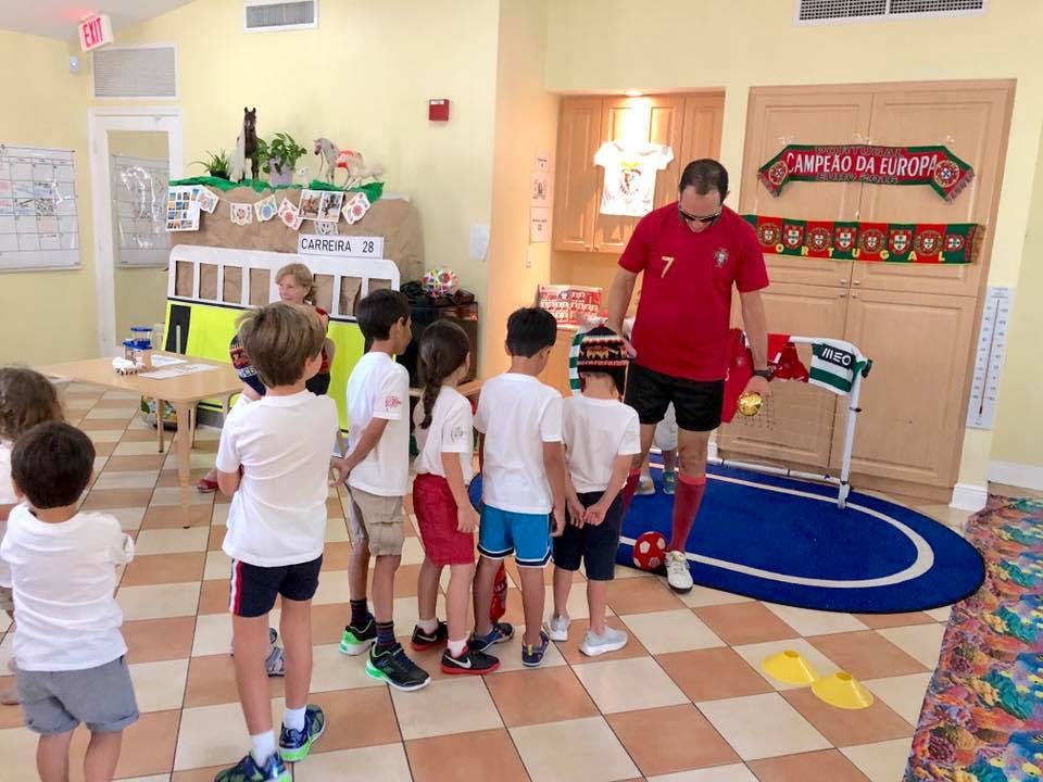 Adult in red shirt with children in white shirts in a classroom