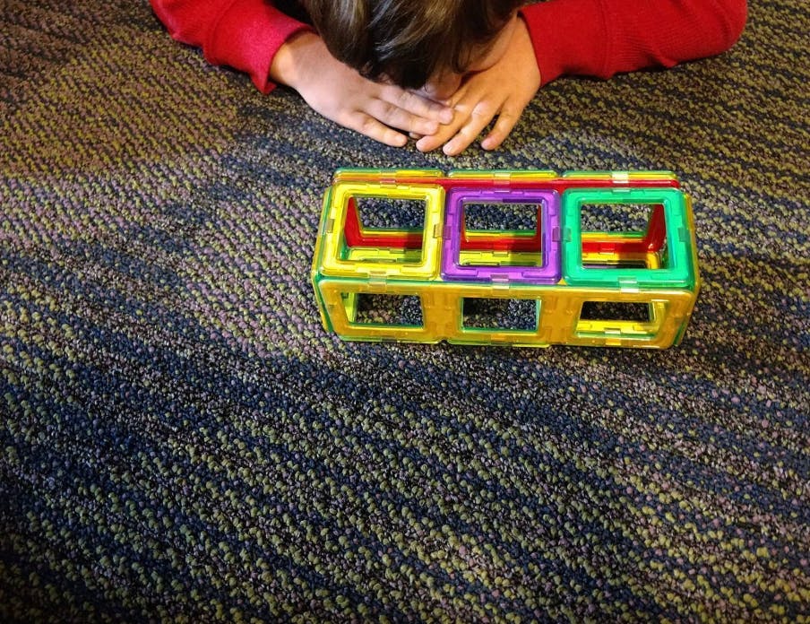 Person on floor with colorful magnetic building toy