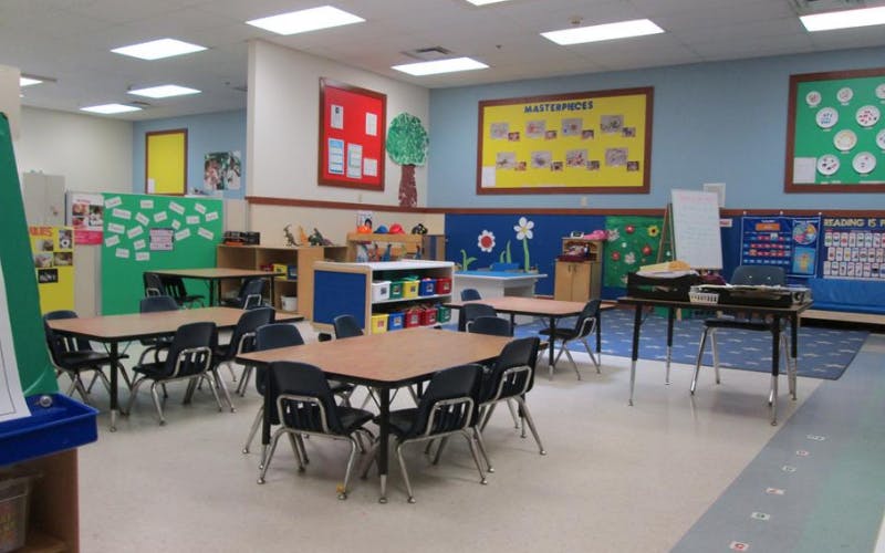 Empty classroom with small tables and chairs, and colorful bulletin boards