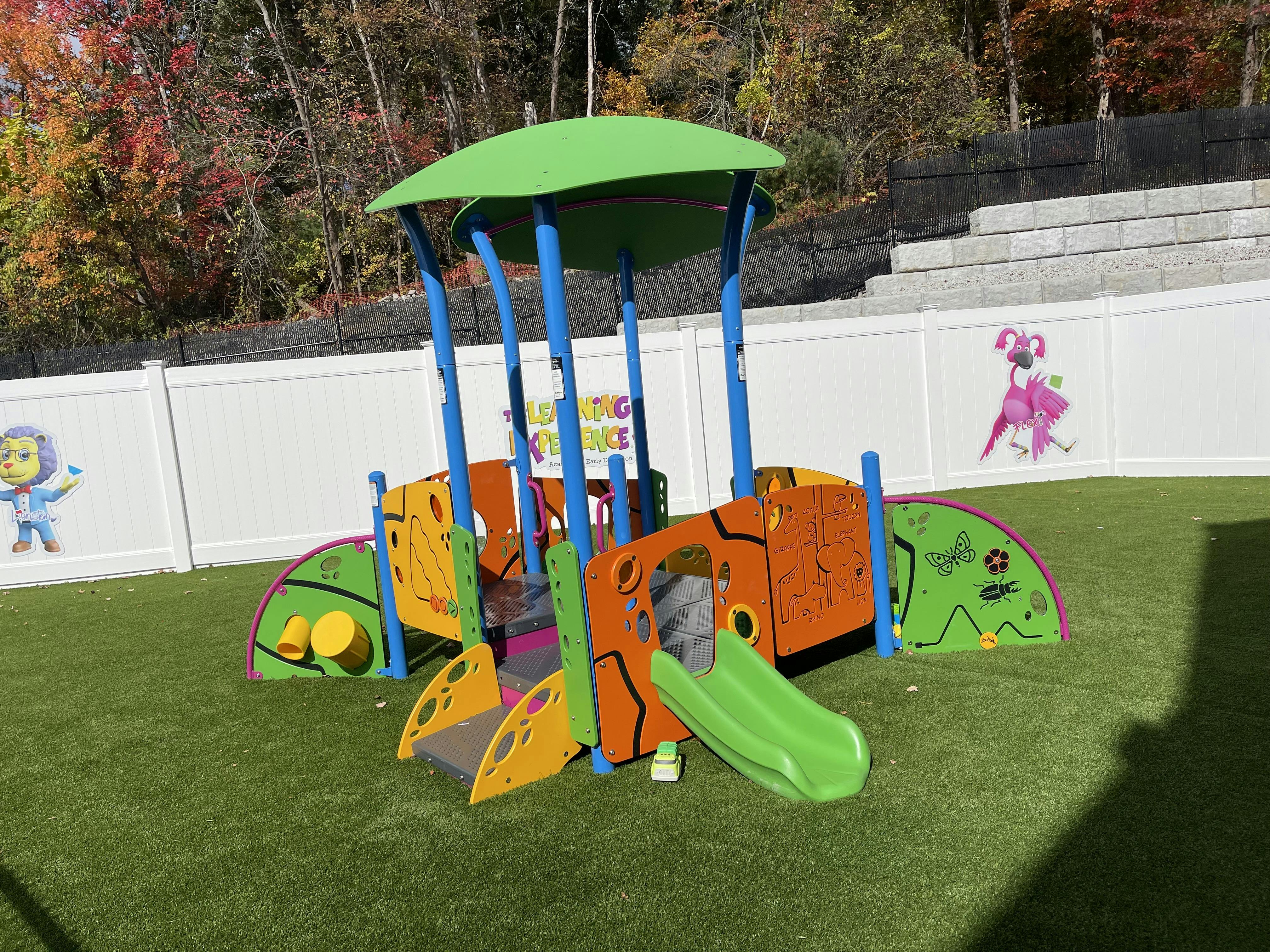 Colorful playground structure with slides and climbing elements on artificial turf