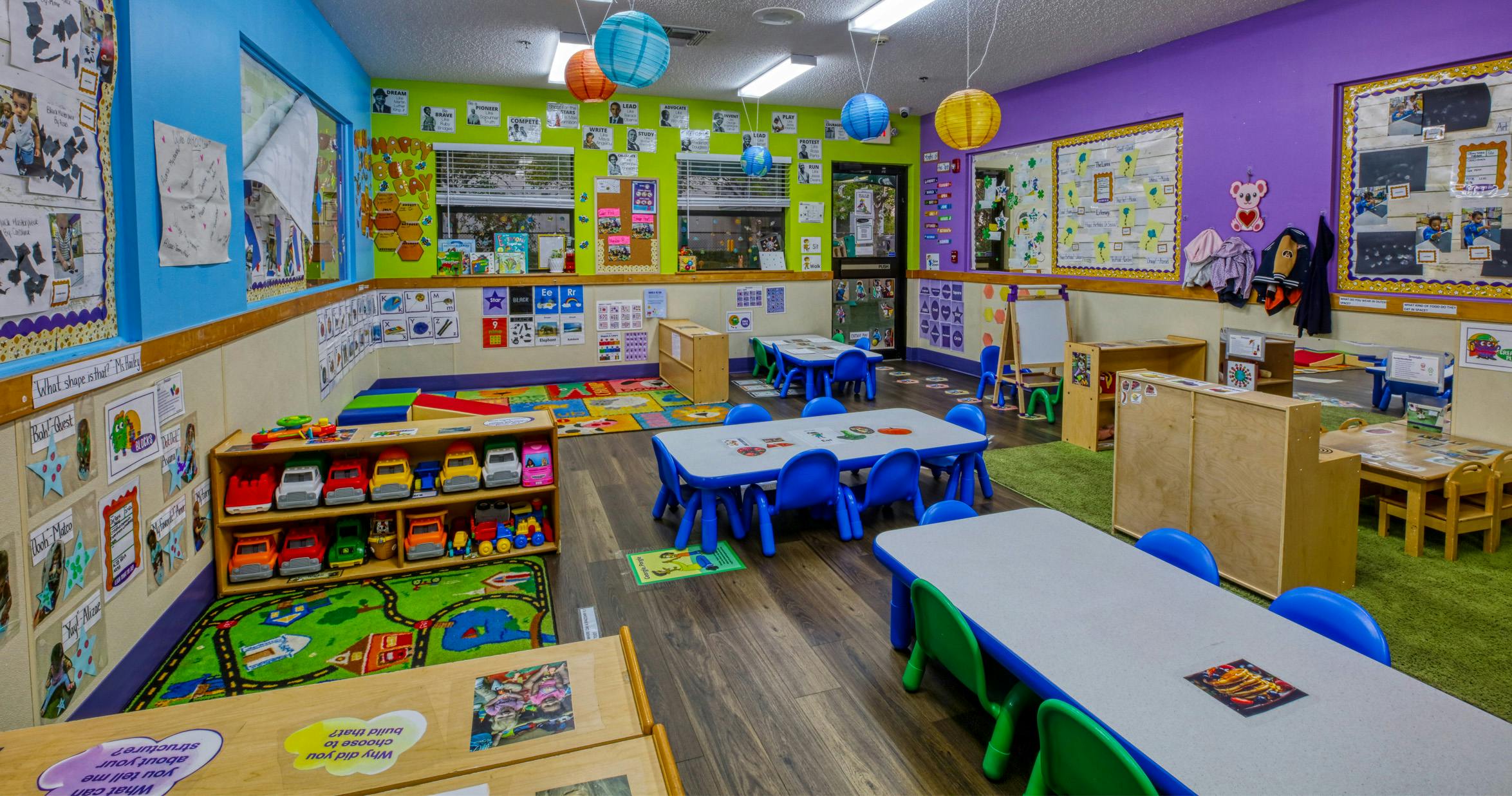An empty early childhood classroom with small tables, chairs, and play areas