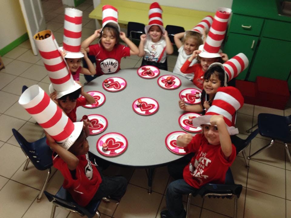 Children wearing red and white striped hats around a table