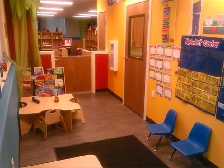 Children's classroom with small tables and chairs, and an alphabet chart
