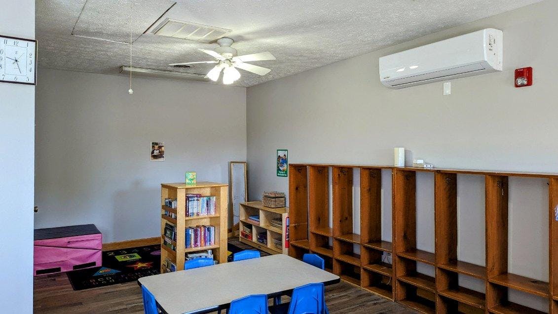 Classroom with tables, chairs, bookshelves, and a ceiling fan