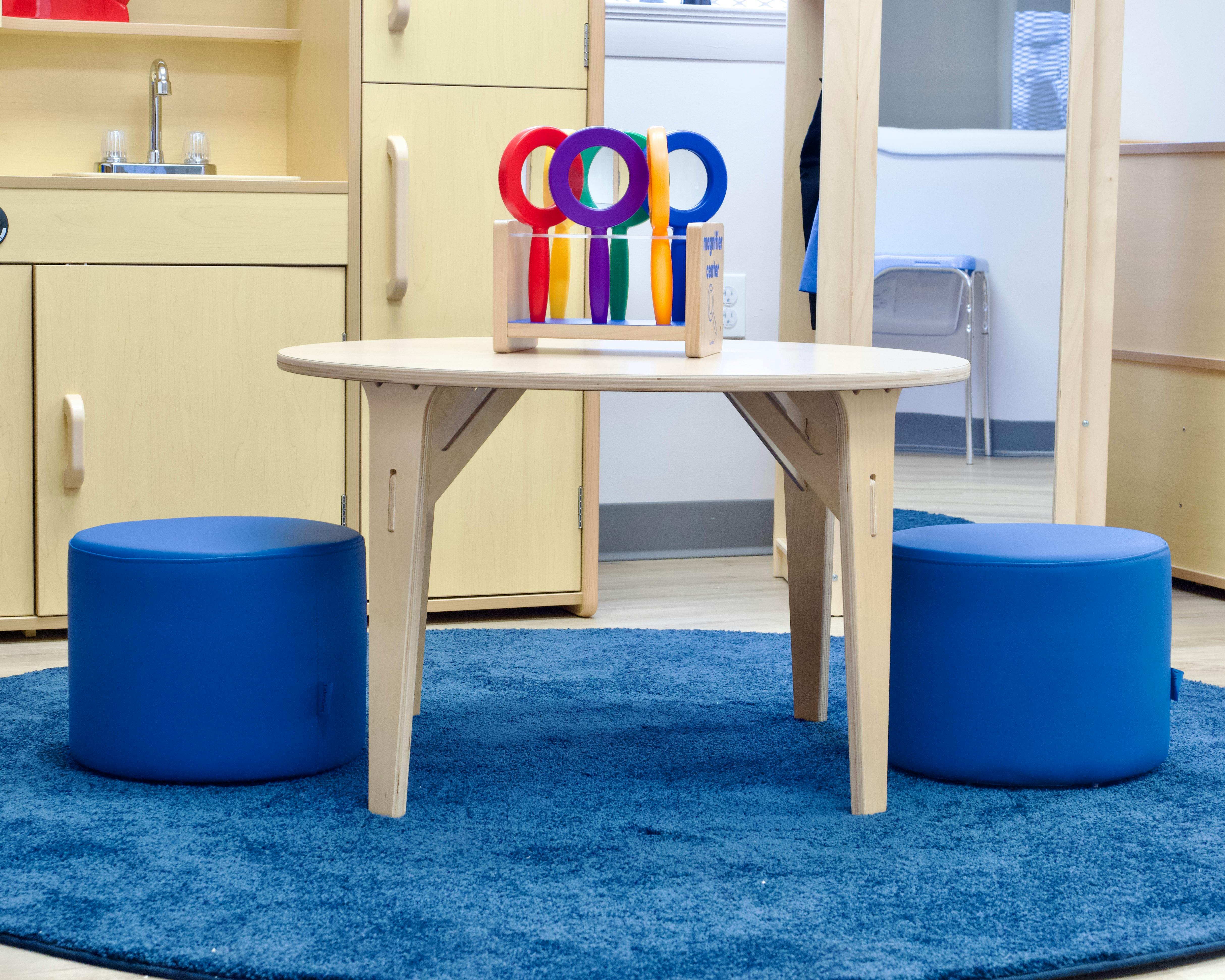 Small wooden table with two blue ottomans on a blue rug