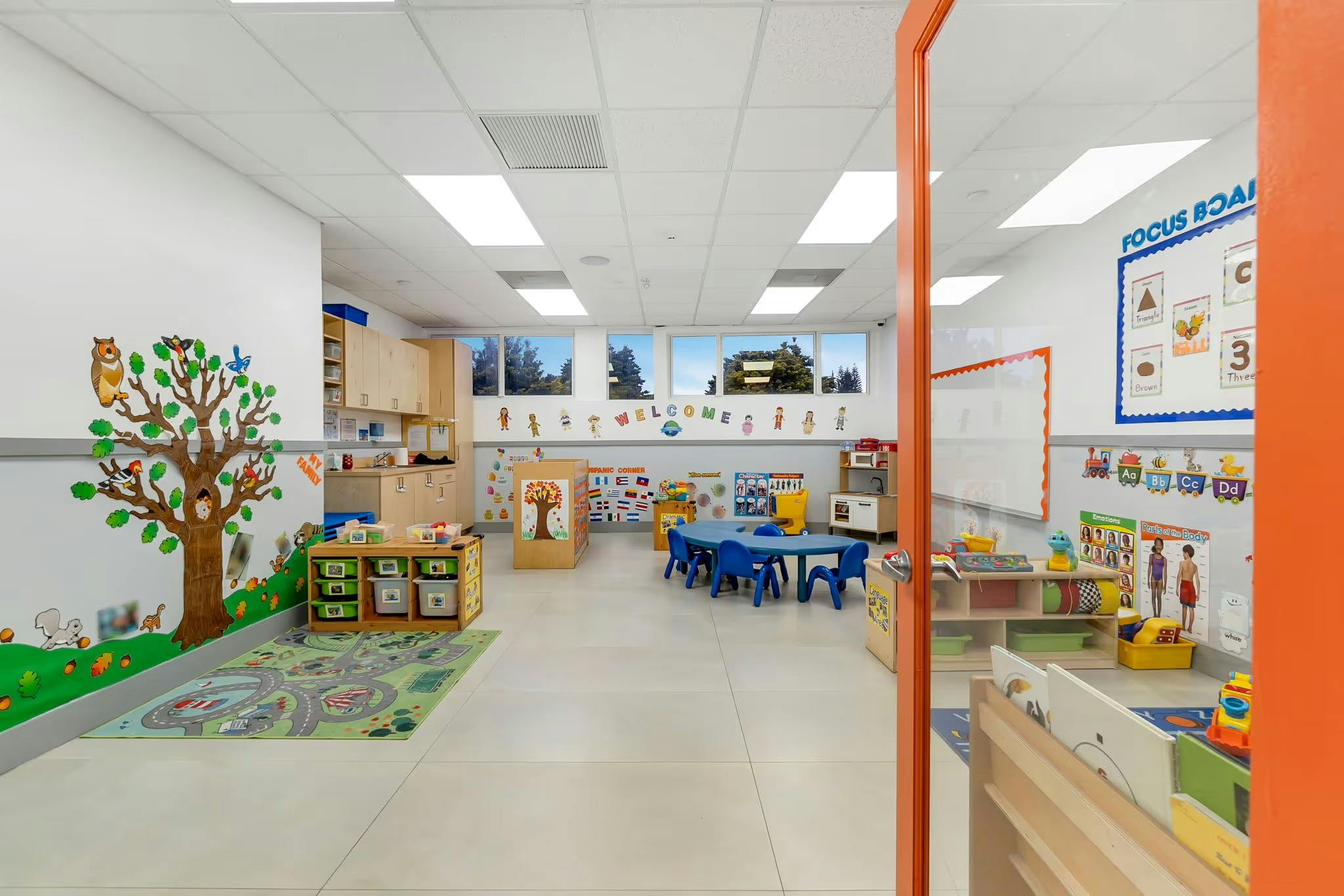 Empty classroom with small blue tables and chairs, wall decorations
