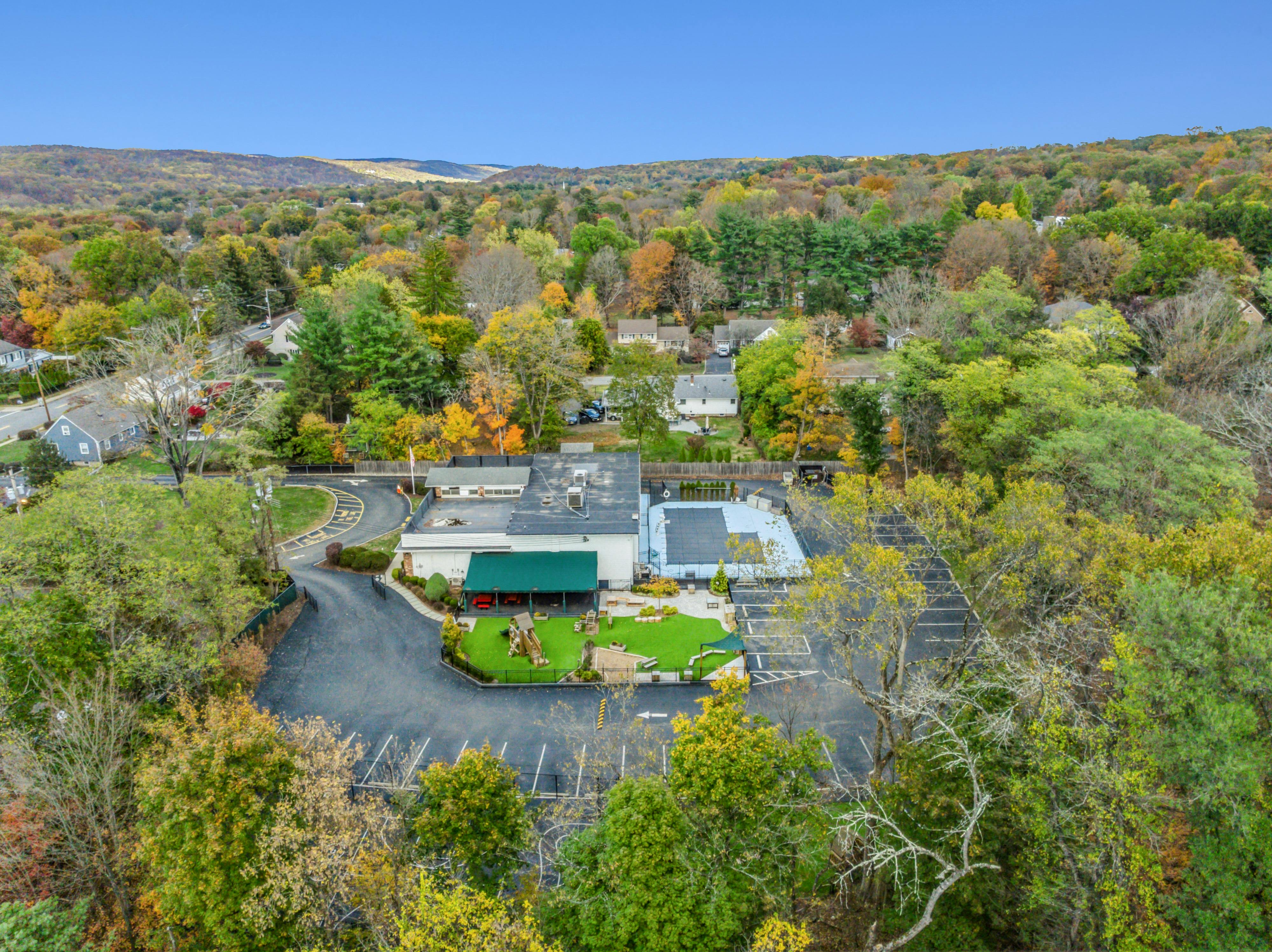 Aerial view of a building with a green awning, playground, and parking lot