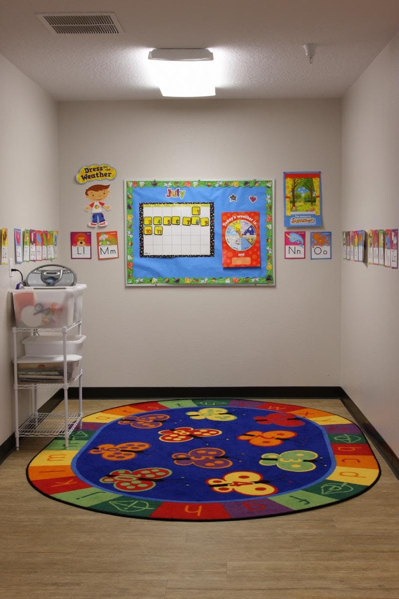 Classroom with a colorful rug, bulletin board, and storage cart