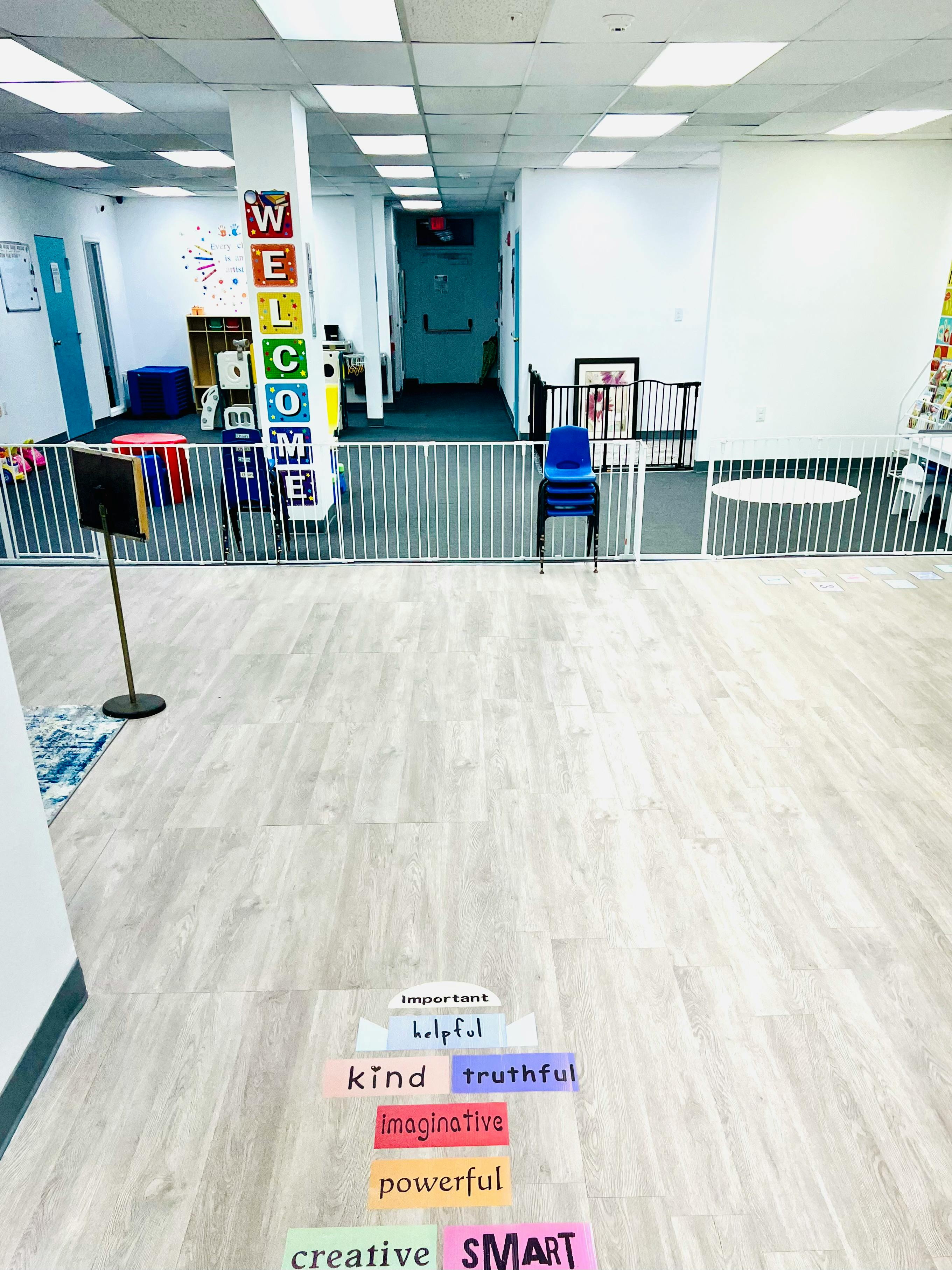 Empty room with a white fence, blue chairs, and a welcome sign