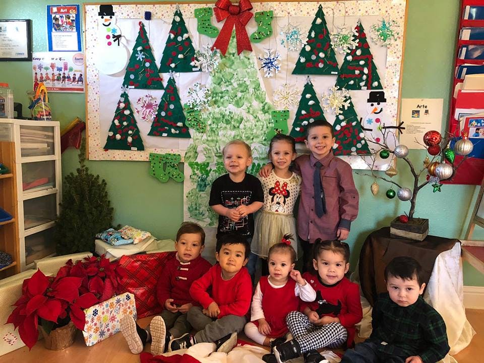 Group of children posing in front of a Christmas-themed wall decoration