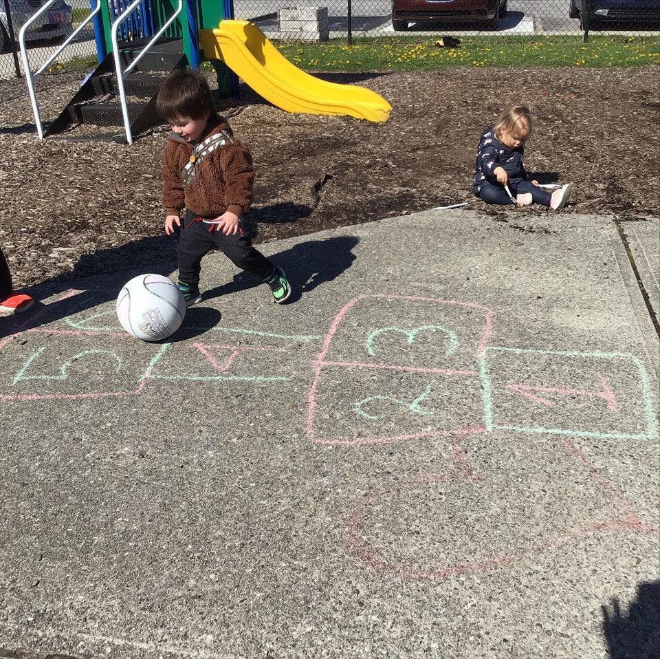 Child playing with a soccer ball on pavement with chalk drawings
