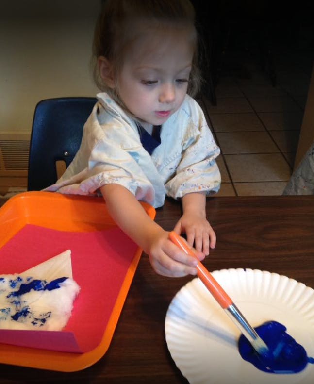 Child painting with blue paint and a brush
