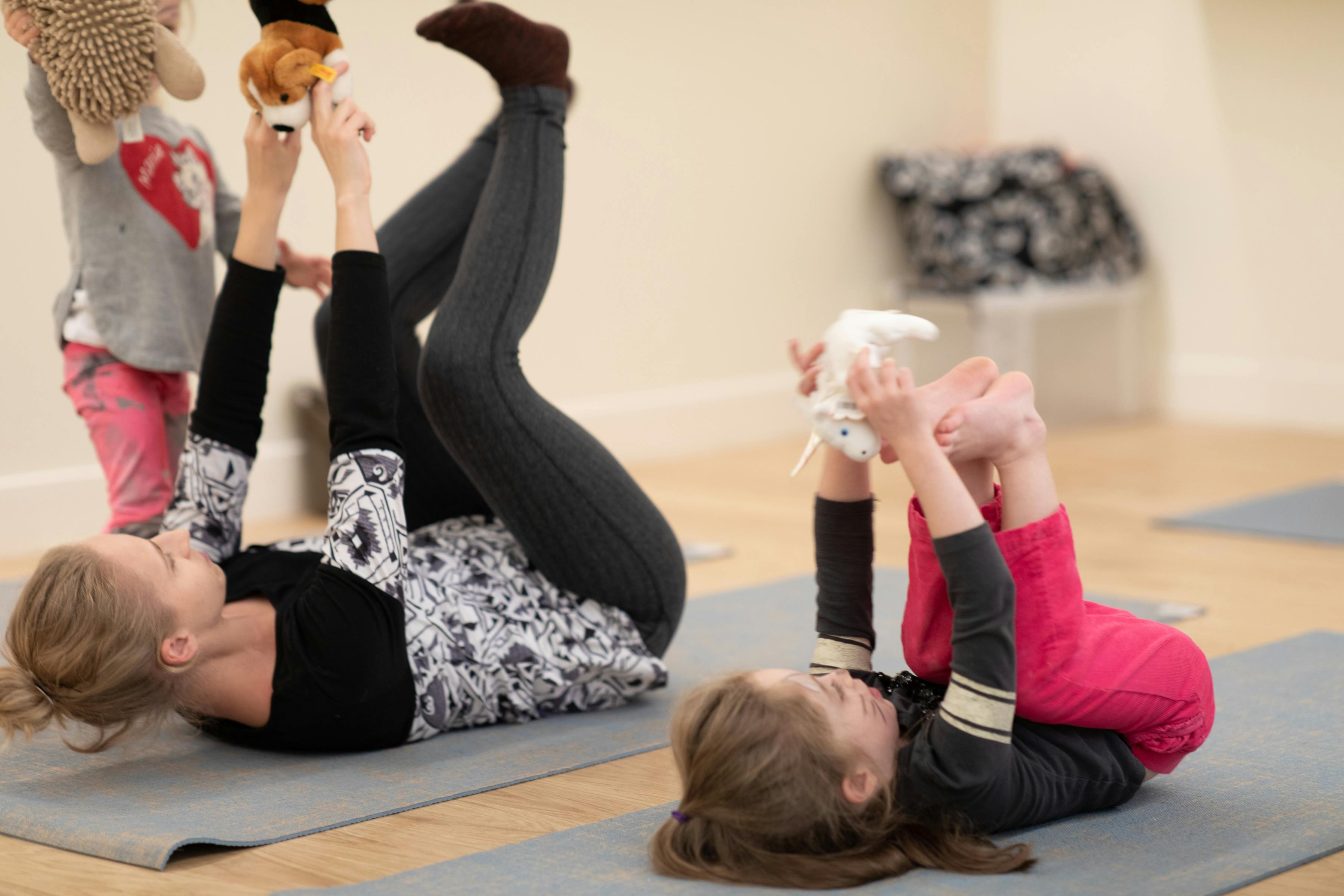 Person and child lying on backs on yoga mats, legs in air