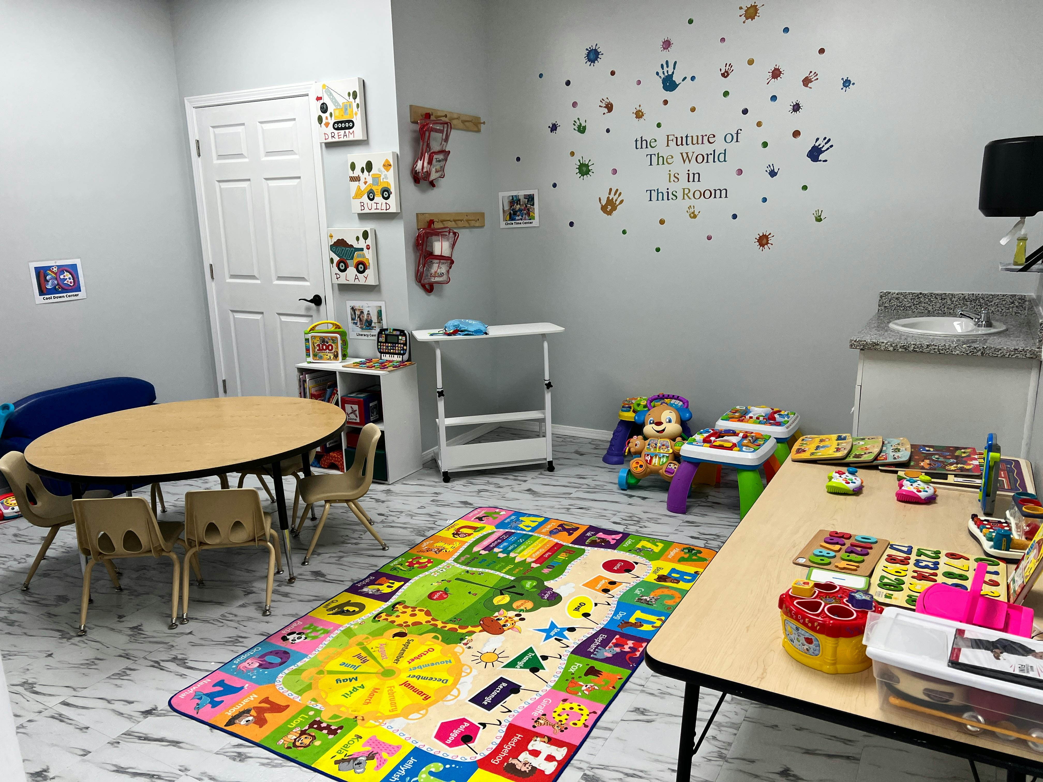 Children's playroom with small tables, chairs, and colorful rug
