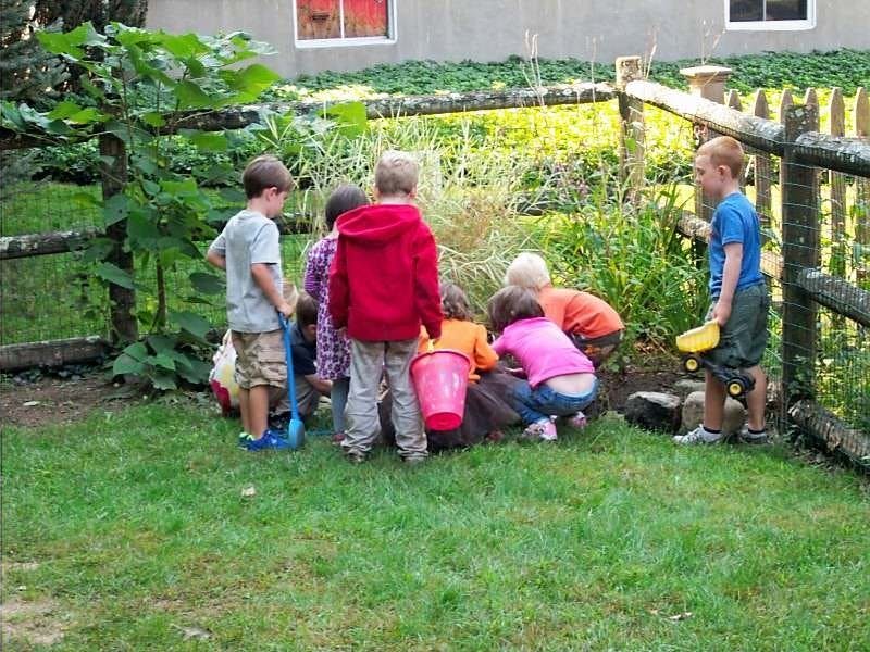 Group of children playing outdoors with buckets and toys