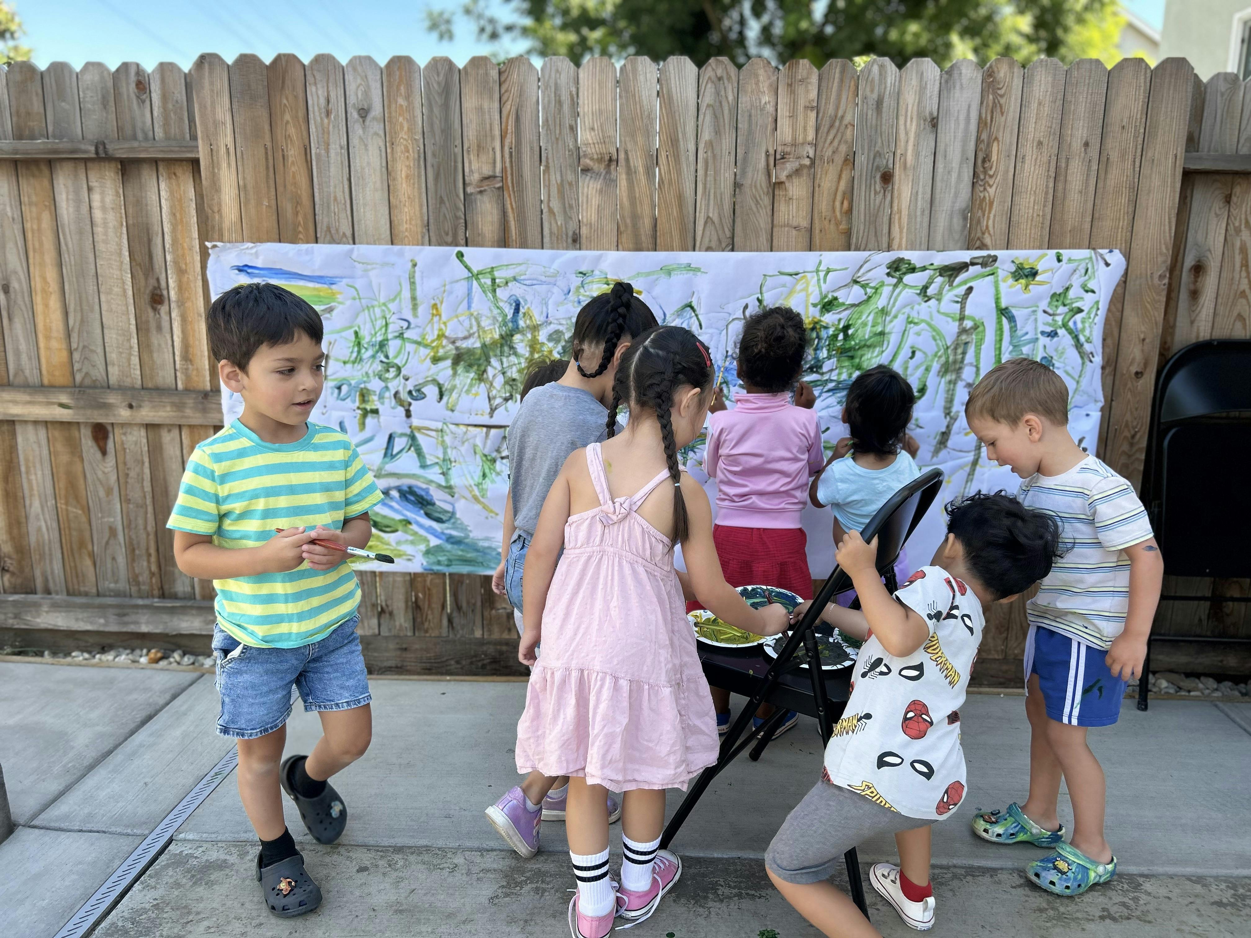 Children painting on a large canvas outdoors