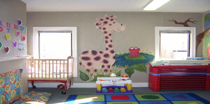 Nursery room with a crib, changing table, and giraffe wall mural