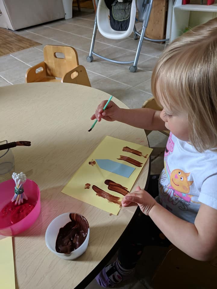 Child painting with a brush on paper atable