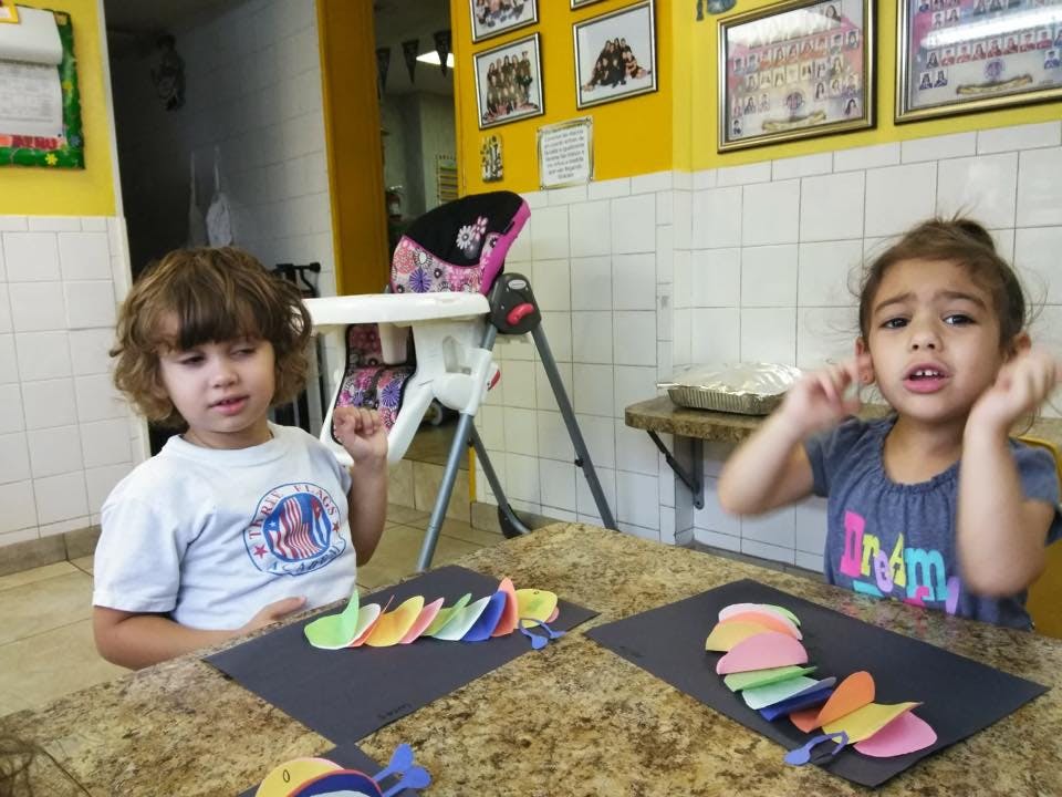 Two children at a table with paper crafts