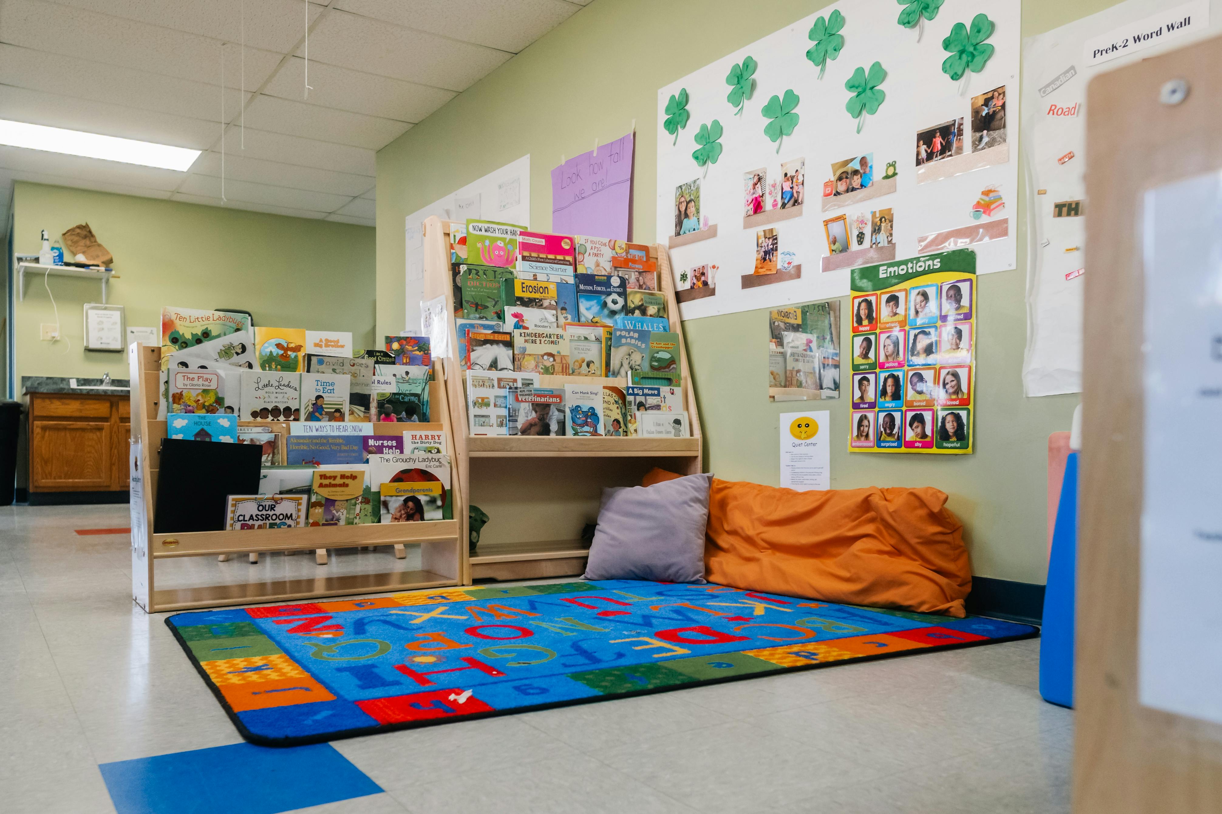 Classroom reading nook with bookshelves, alphabet rug, and emotion chart