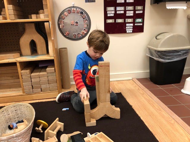 Child playing with wooden blocks on a rug