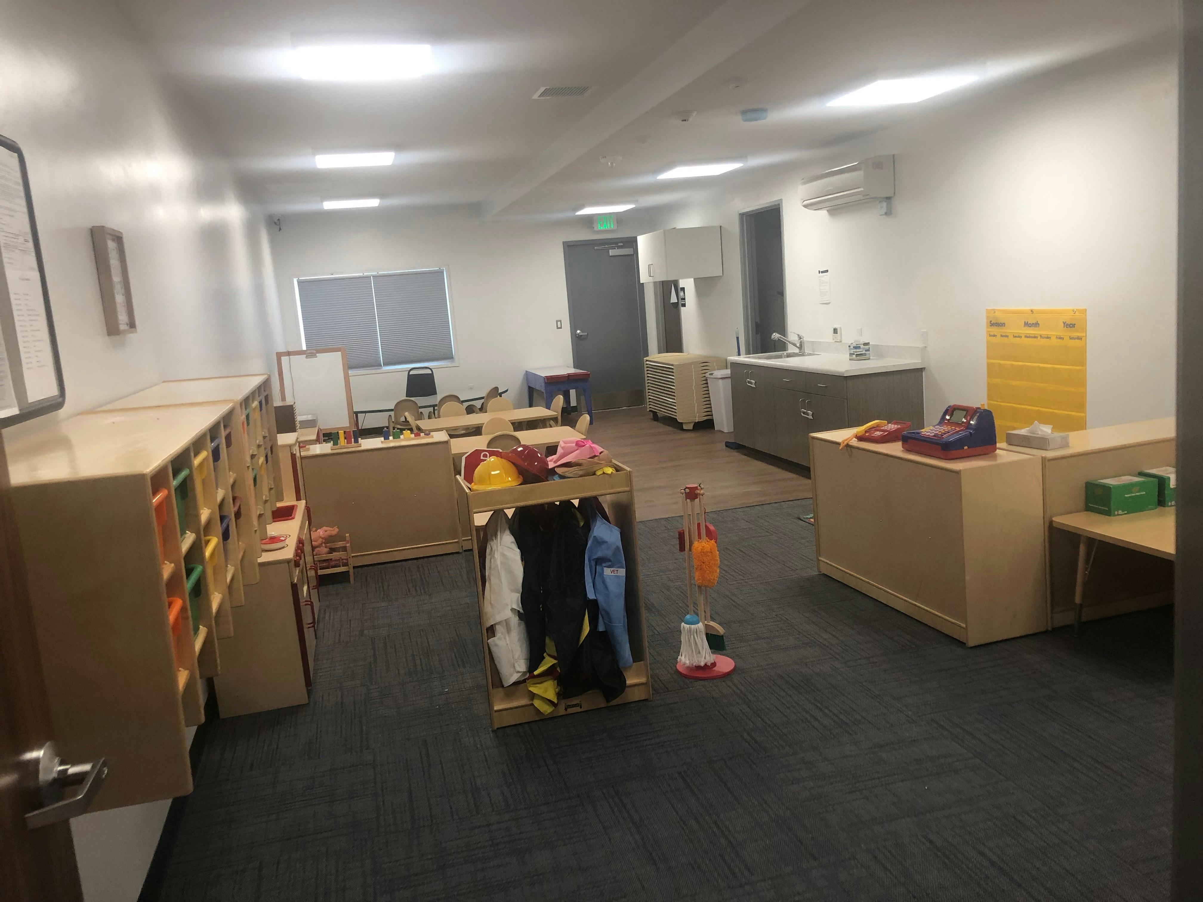 Empty classroom with small tables, chairs, and storage units