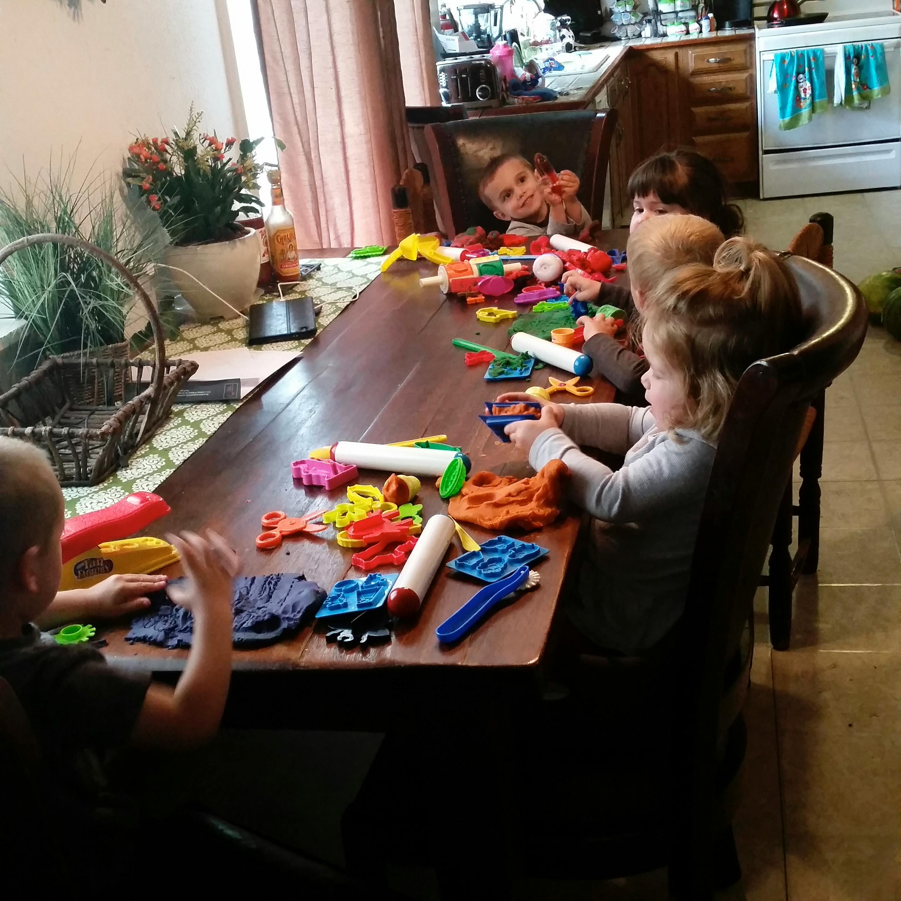 Children playing with modeling clay and tools at a table