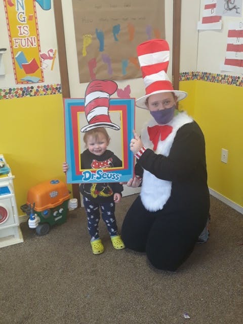 Person in Cat in the Hat costume with child holding Dr. Seuss cutout