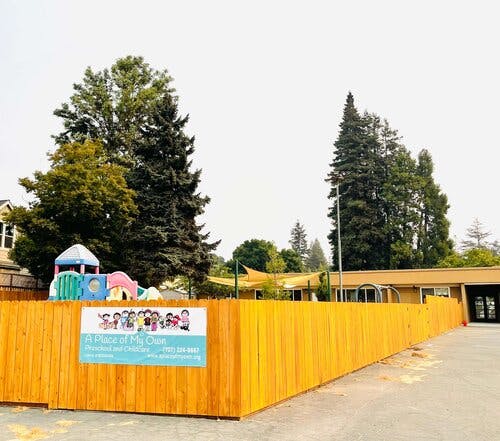 Playground with colorful equipment behind a wooden fence