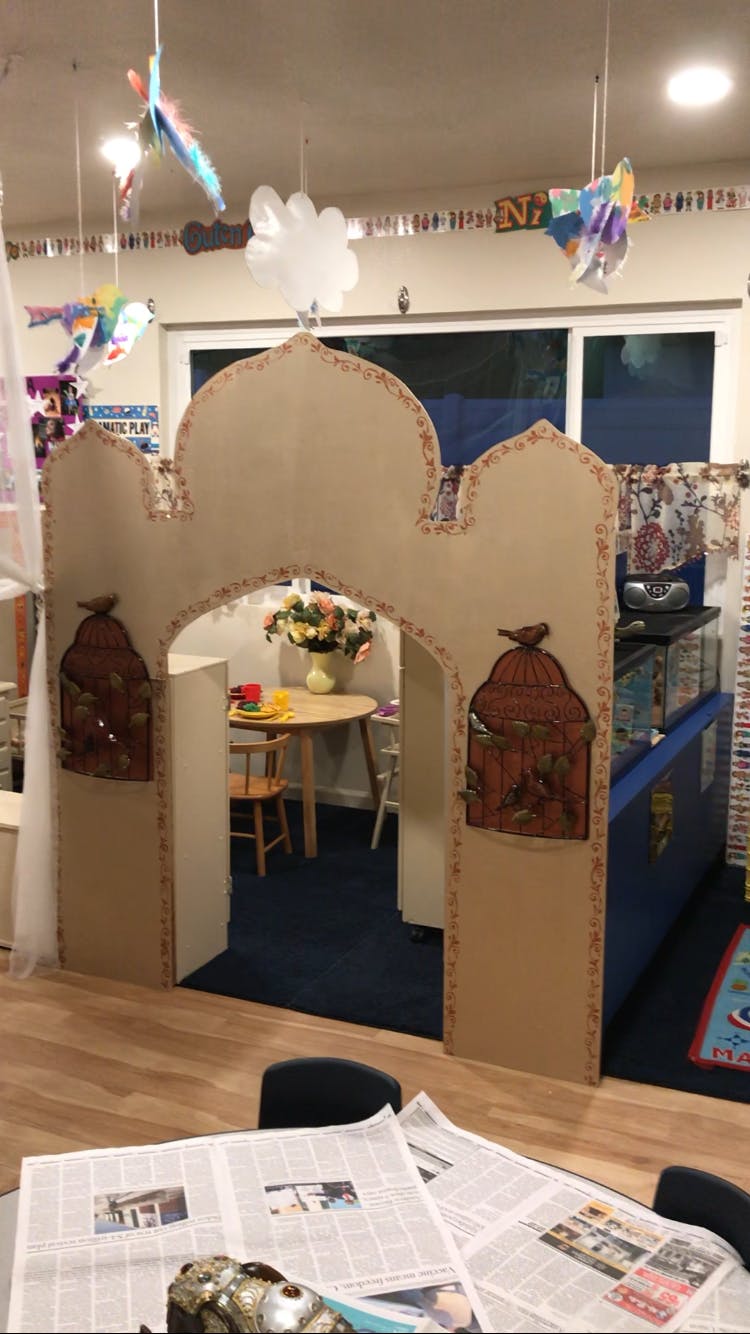Cardboard archway with birdcage decorations leading to a small table and chairs