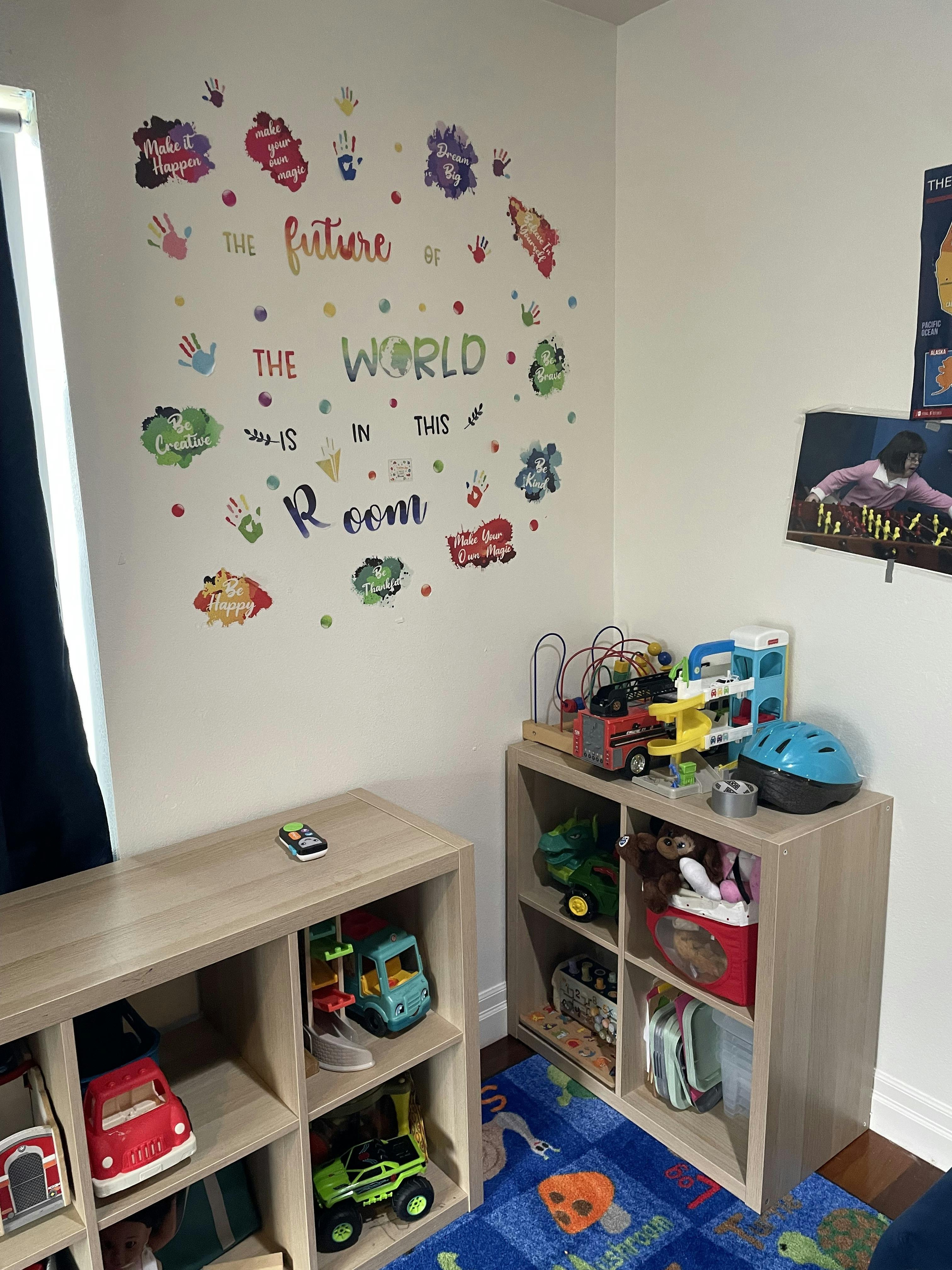 Playroom wall decal with text and children's toy storage units