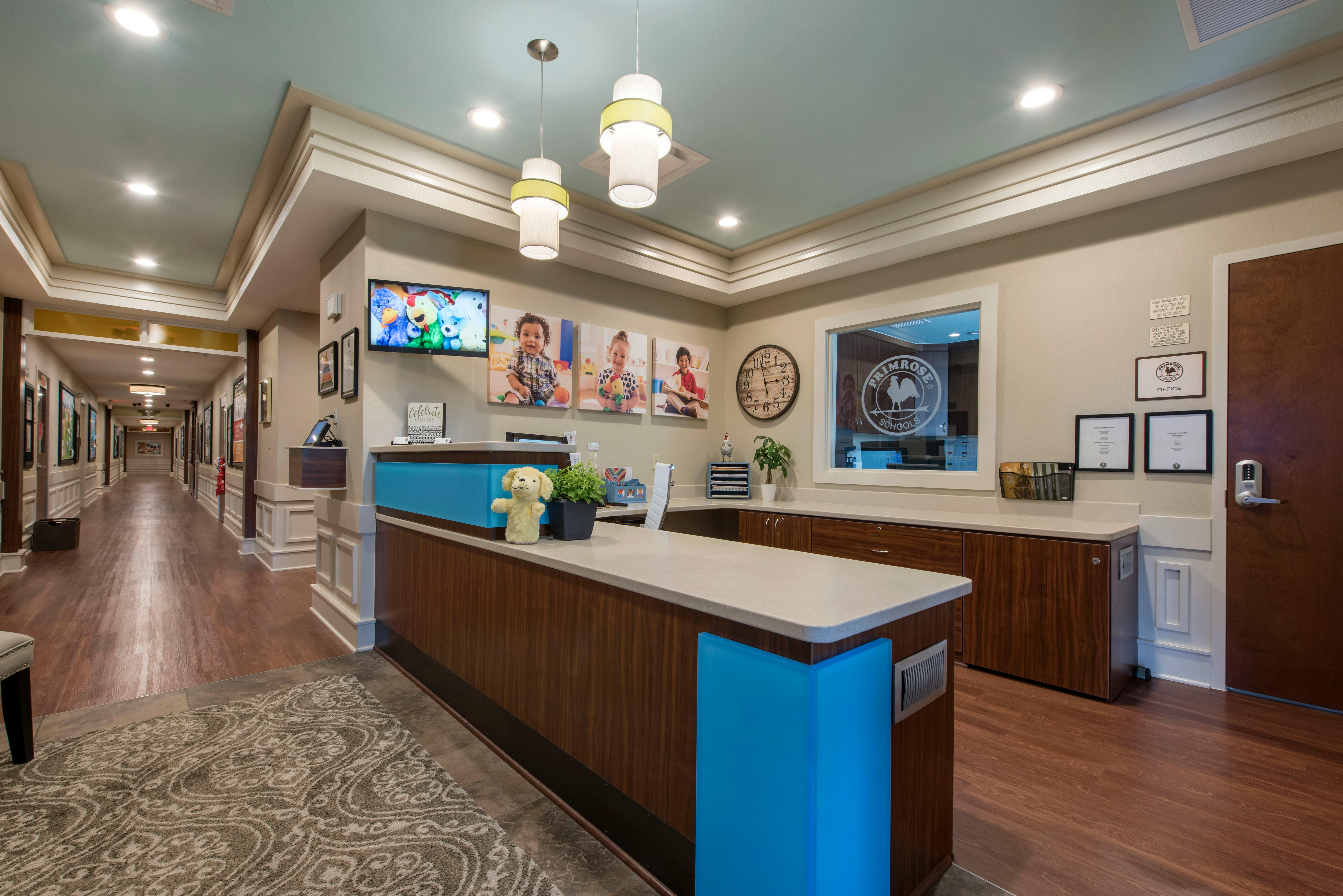 Reception area of a school with a long hallway, desk, and children's photos