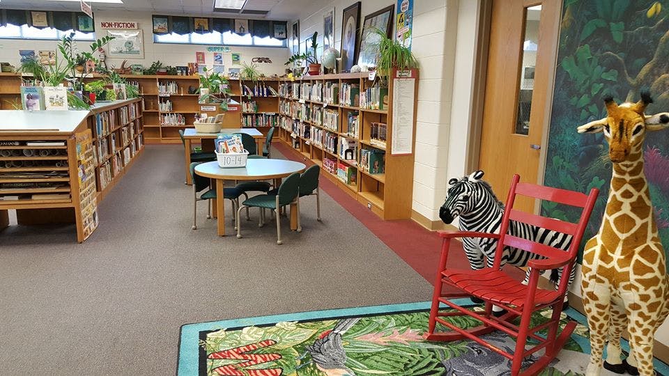 Library with bookshelves, tables, chairs, and animal statues