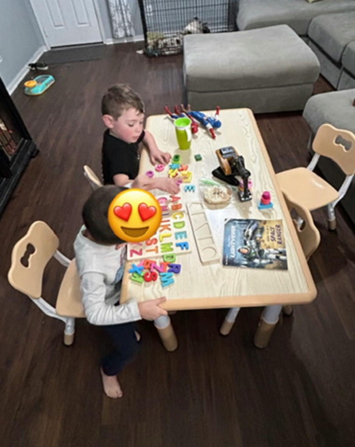 Two children playing with alphabet puzzle pieces at a small table