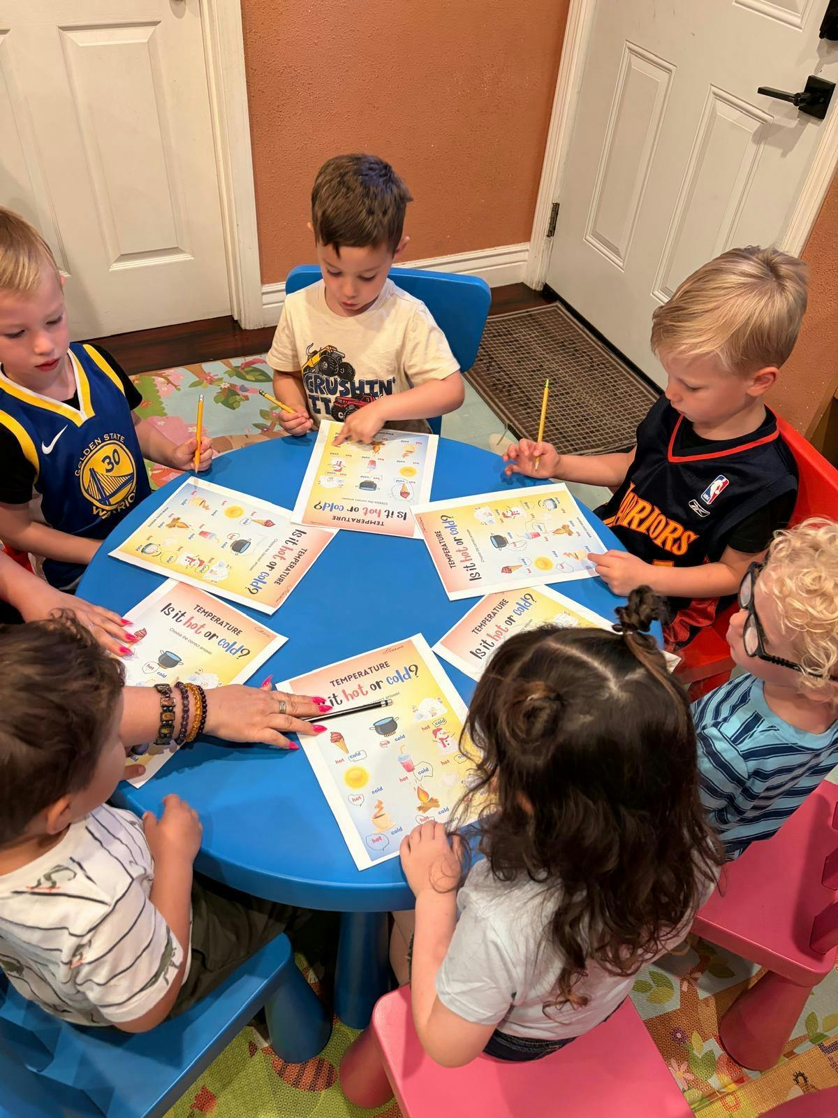 Children learning about temperature with worksheets titled "Is it hot or cold?"