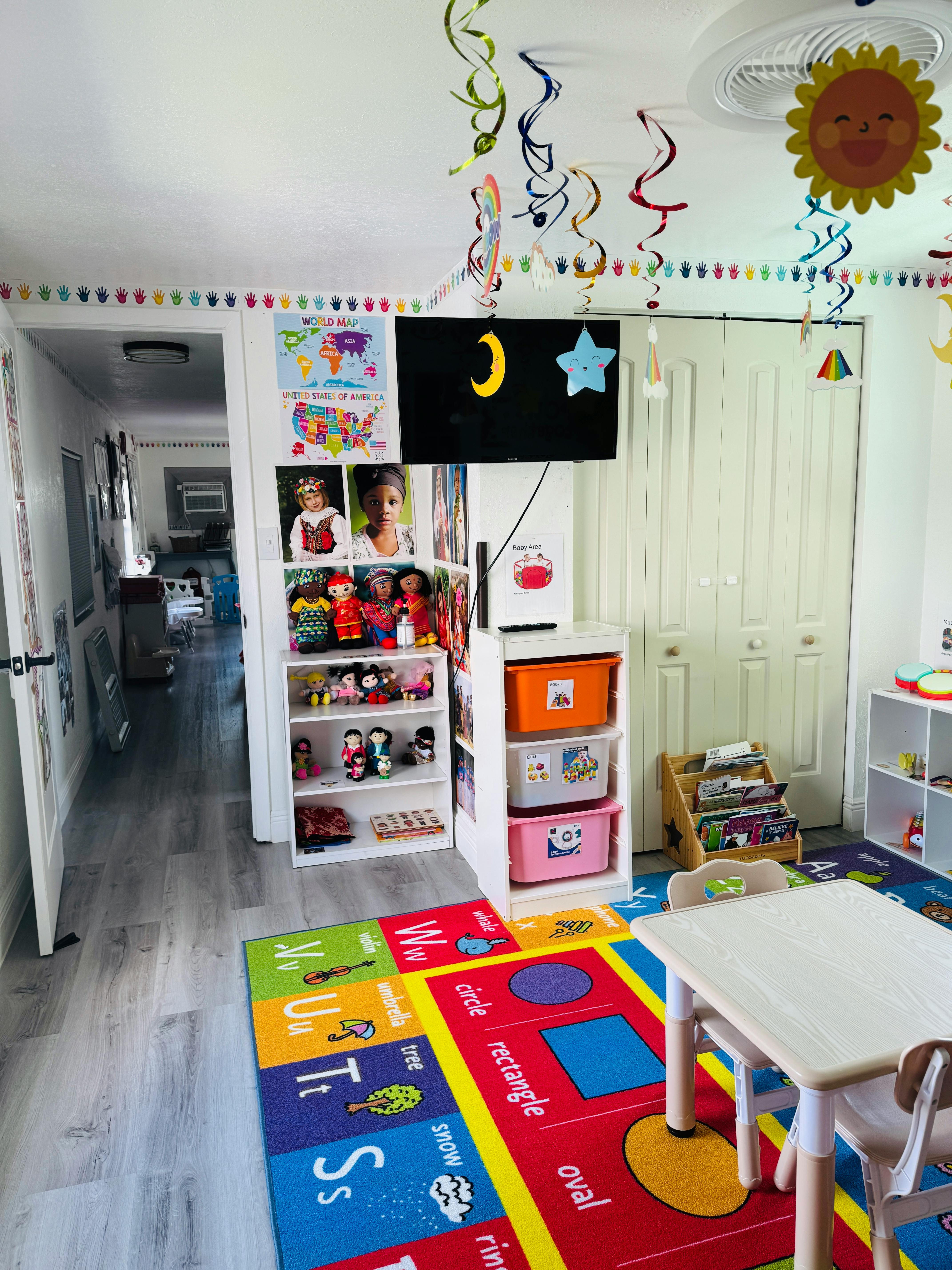 Playroom with alphabet rug, shelves of toys, and small table with chairs