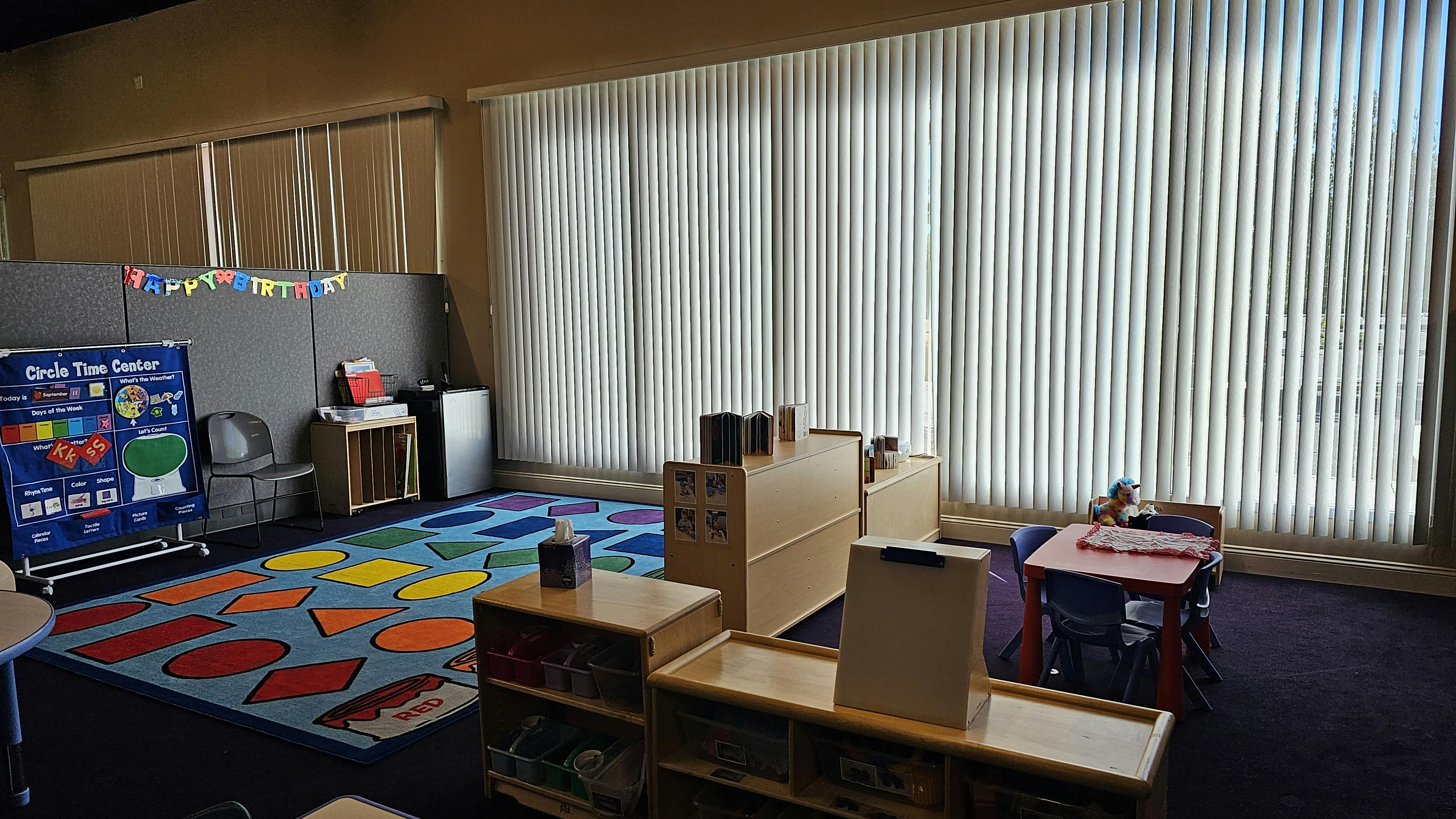 Classroom with a colorful shape rug and small furniture