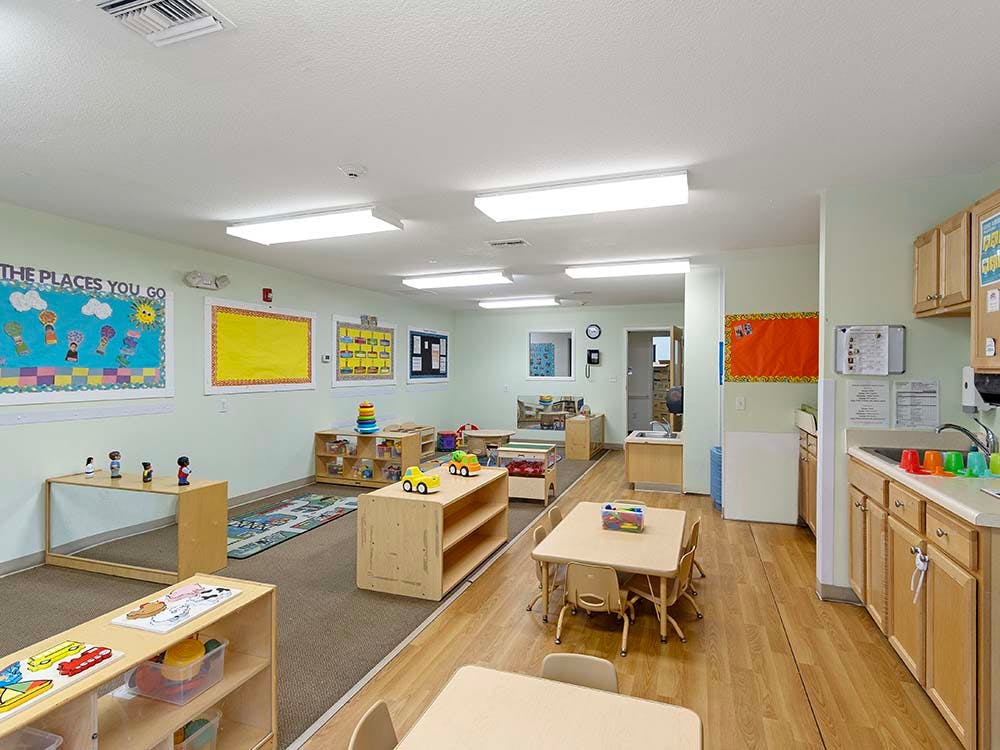 Classroom with child-sized furniture, play mats, and a kitchenette
