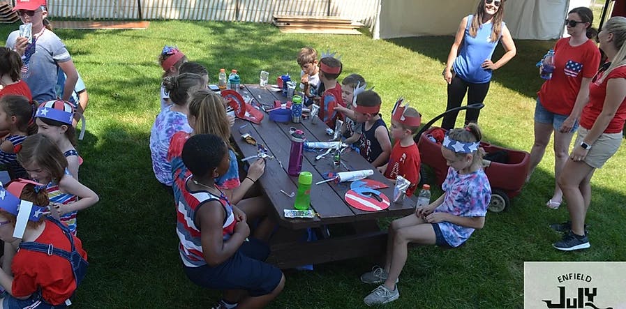 Children and adults gathered around a picnic table outdoors