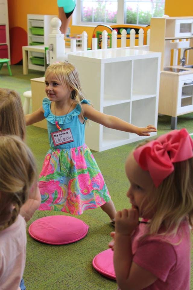 Child standing with arms out in a classroom