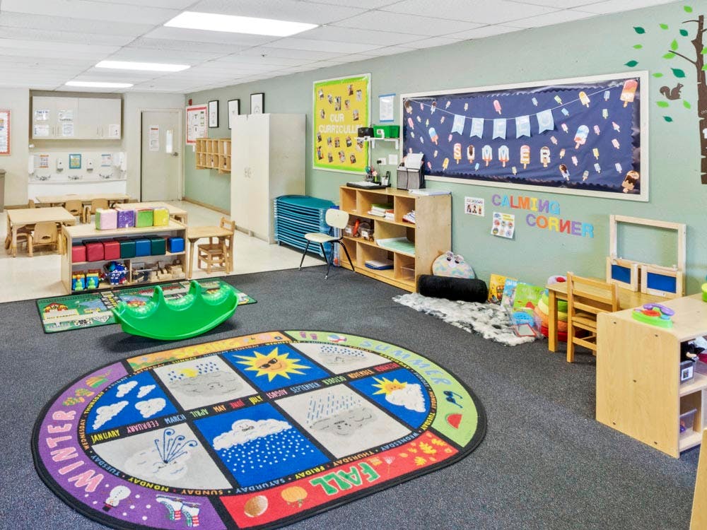 Colorful preschool classroom with various activity areas, small tables and chairs