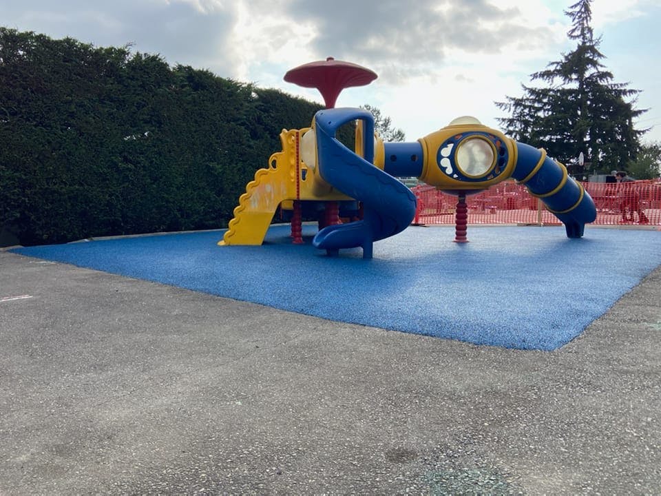 Playground with blue, yellow, and red play structure on blue ground