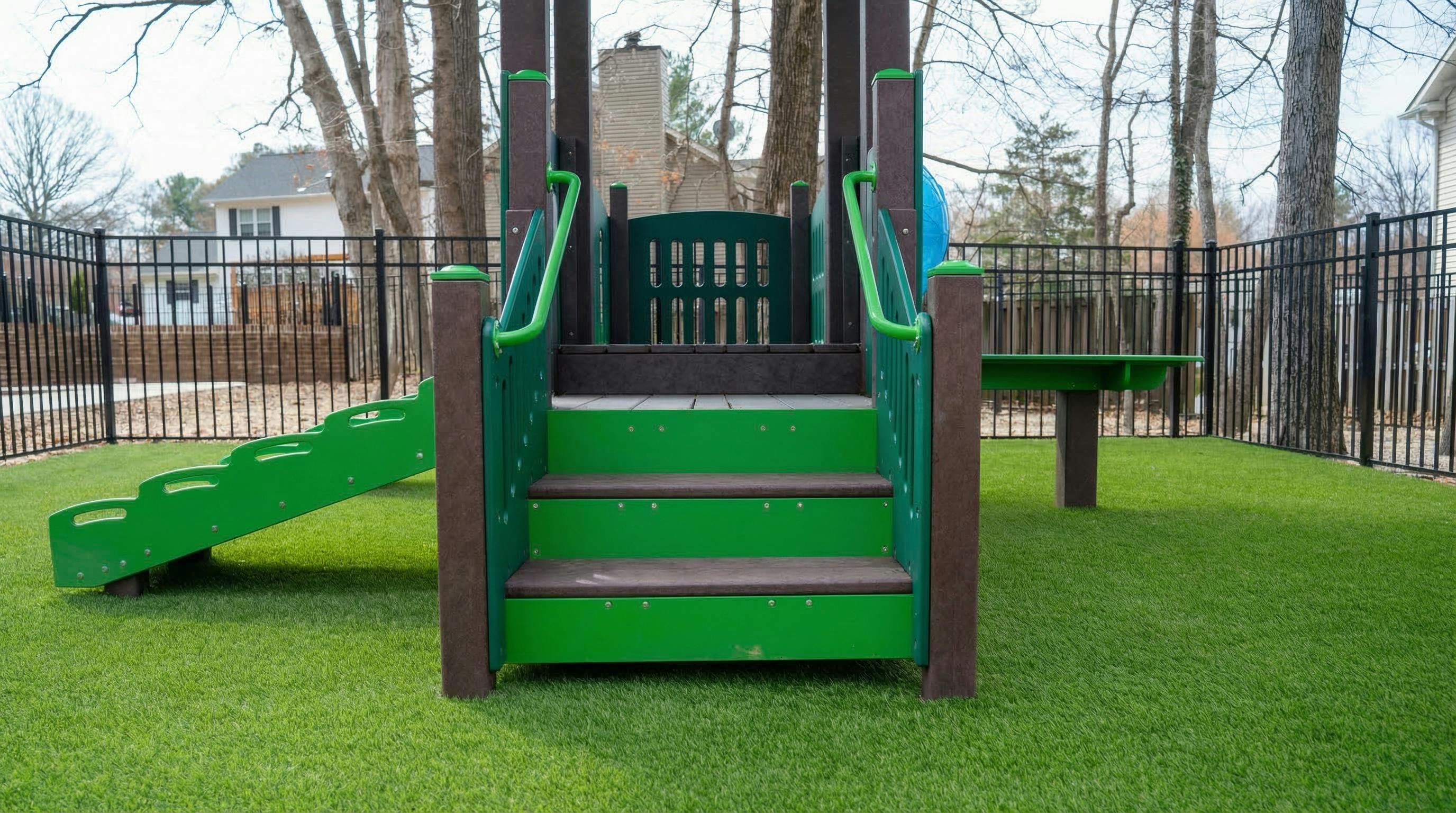 A green and brown playground set on artificial green turf