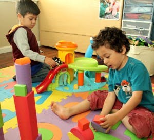 Two children playing with toys on a colorful mat