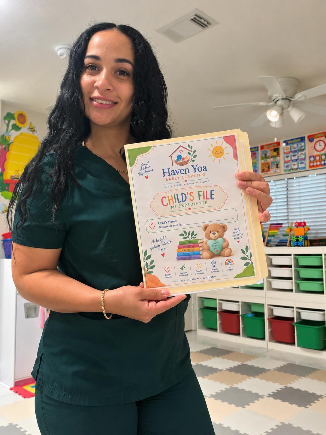 Person in a classroom holding a file folder labeled Haven Yoa Early Learning