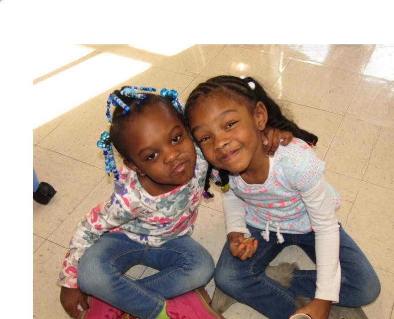 Two children sitting together, one with arm around the other